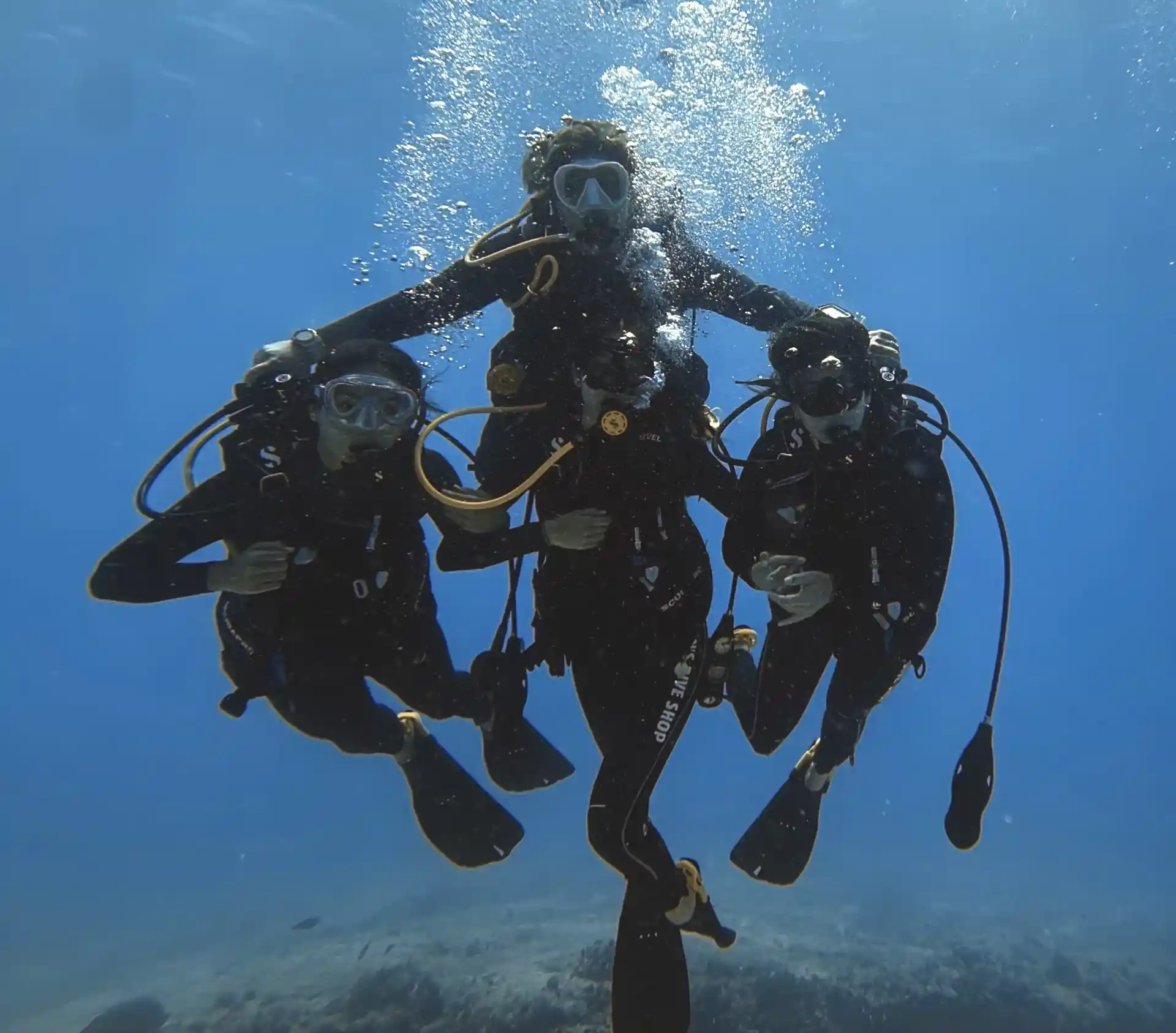 A PADI instructor guides three students through their training dives, helping them develop the skills and confidence needed to become certified divers.