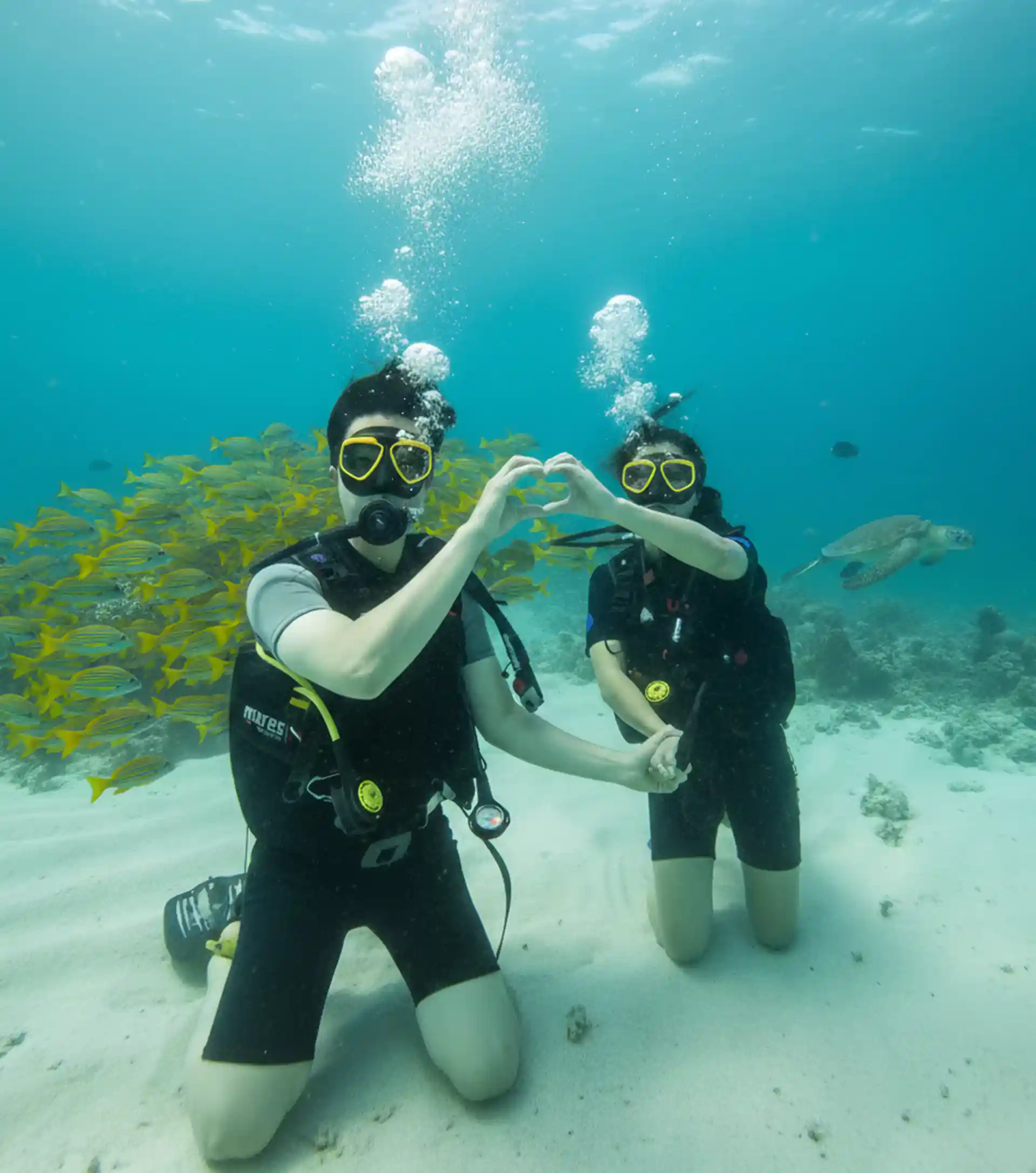 Two beginner divers forming a heart shape with their hands during a Discover Scuba Diving dive.