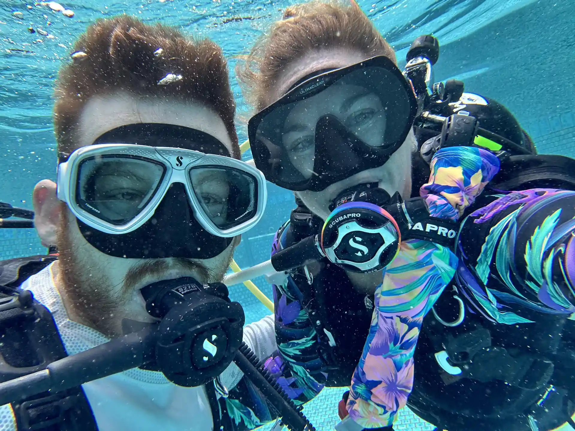 An instructor and student capture a fun underwater selfie during pool training while building skills, confidence, and excitement for their upcoming ocean dives.