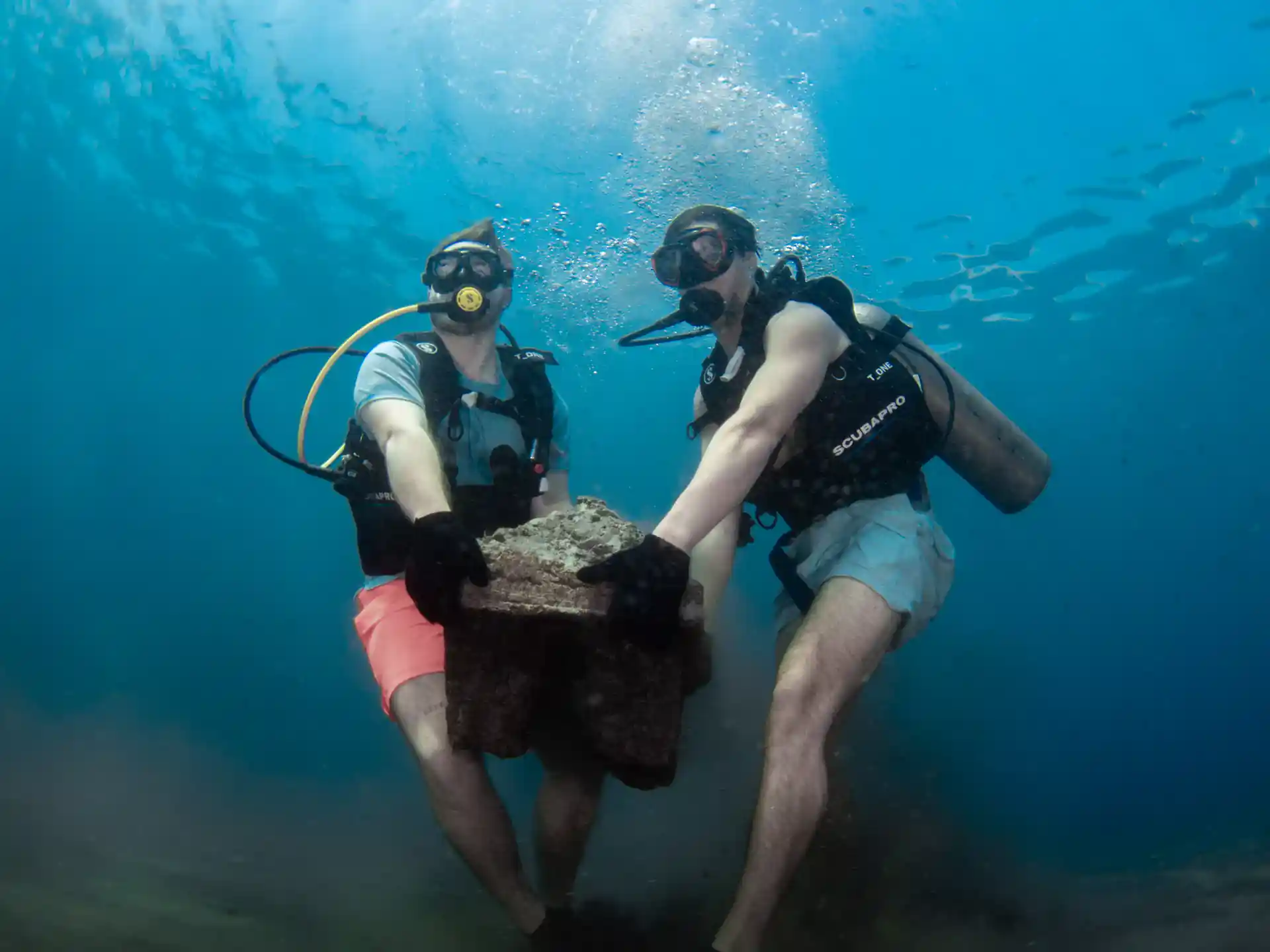 BCD divers buddy team deploying an artificial reef structure in Tulamben, Bali