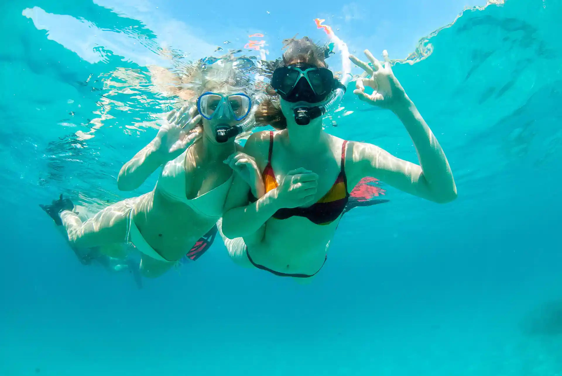Two girls exploring vibrant turquoise waters, snorkeling under the summer sun.